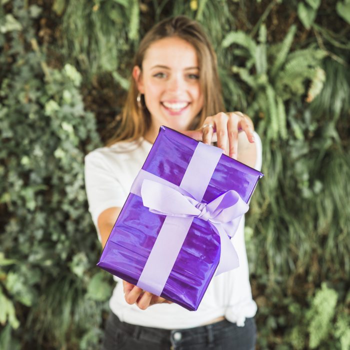 smiling-young-woman-showing-purple-gift-box